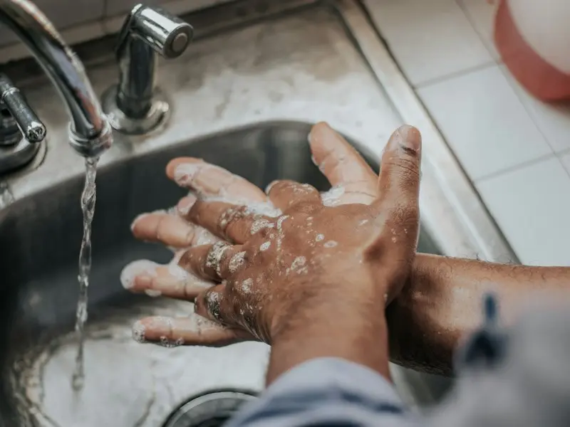 Hands being washed with soap under a running tap