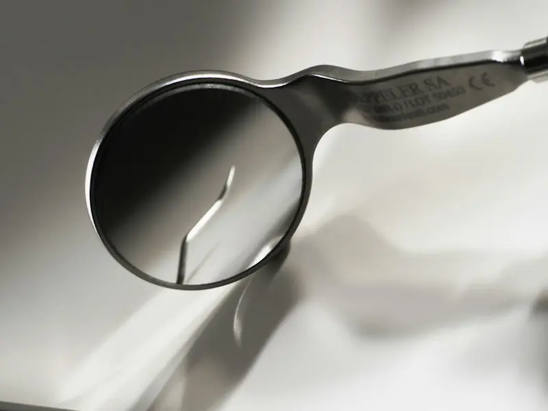 A dental mirror and probe on a white surface