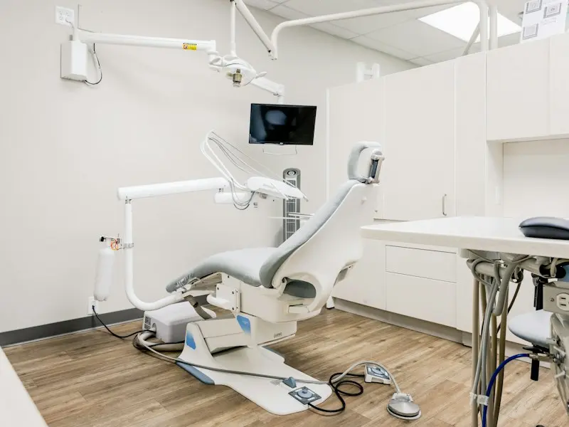 One of our dental surgeries: a white chair with an overhead light and a wall-mounted screen